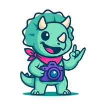 A cute cartoon rhinoceros character holding a camera, smiling and giving a peace sign.