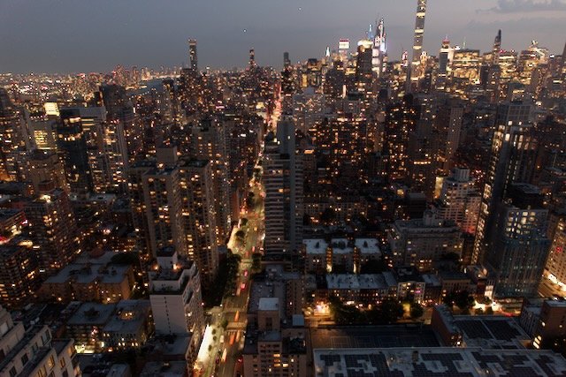 Aerial view of a city skyline at night with illuminated skyscrapers and busy streets, showcasing vibrant urban life.
