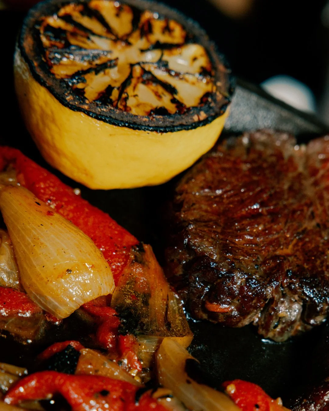 Get your last taste of the cozy winter season with a dry aged NY strip steak served sizzling with roasted peppers, and spring onions