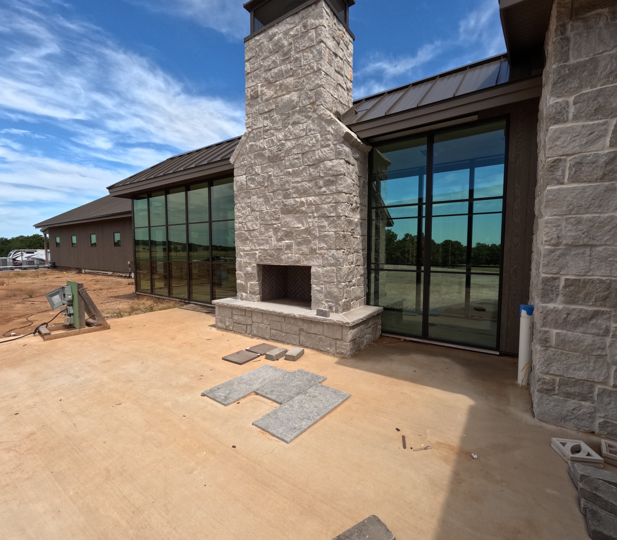Stone fireplace and glass corridor at The Essex Ranch showcasing Marvin windows and views of the surrounding Texas landscape.