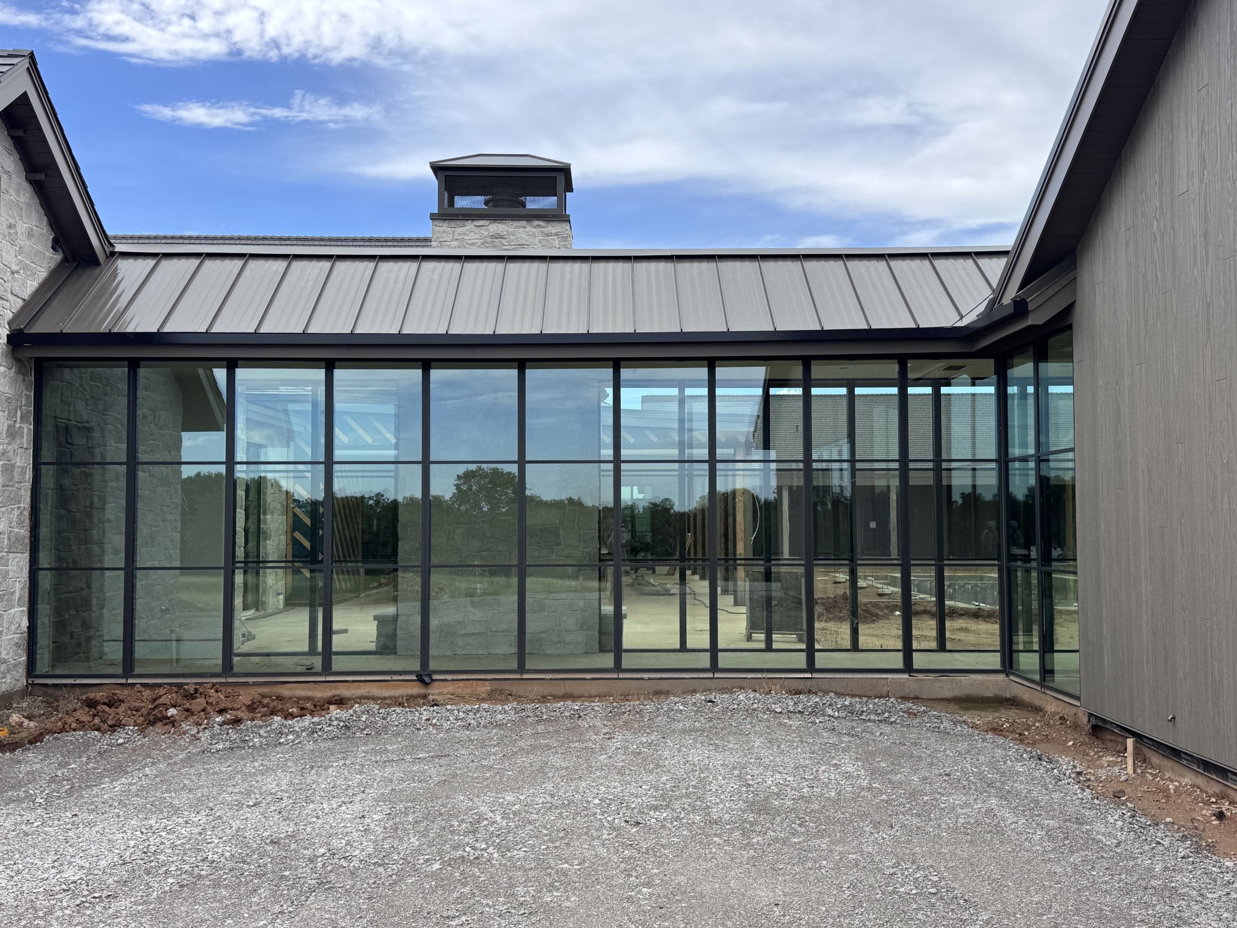 Exterior view of the glass corridor at The Essex Ranch featuring black steel Marvin windows and views of the Texas ranch landscape.
