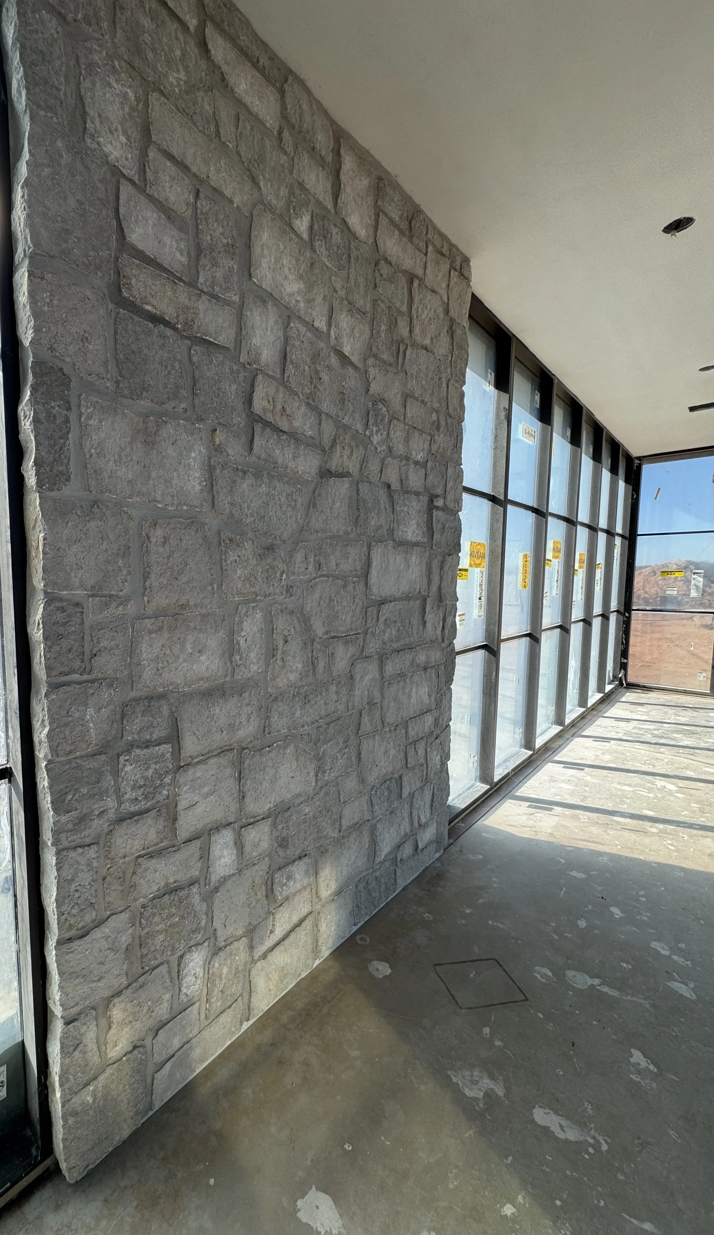 Close view of interior stone wall beside floor-to-ceiling windows at The Essex Ranch