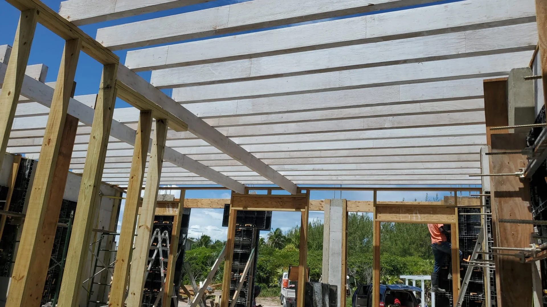Construction site with wooden framework and scaffolding, blue sky in the background.