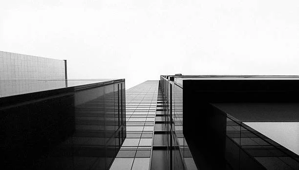 Looking up at a modern skyscraper with glass windows from the ground, capturing the building's height and reflective surface.