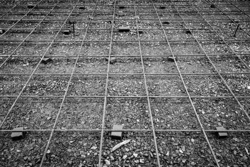 Steel reinforcement bars laid out over gravel for concrete pouring.