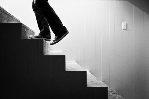 Close-up of a person walking up a staircase, captured from below in black and white.