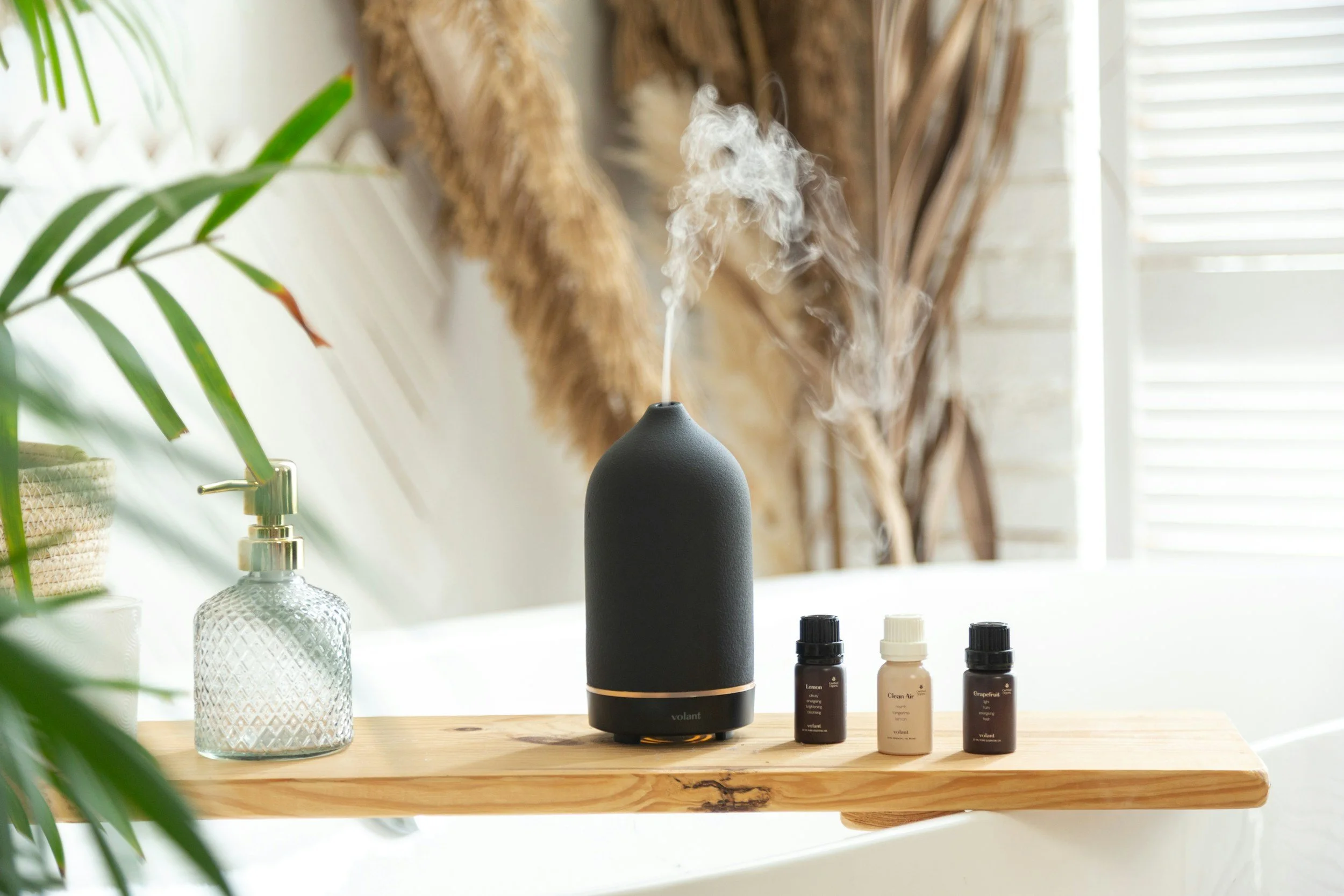 Essential oil diffuser releasing aromatic mist beside oil bottles for a calming jasmine aromatherapy ritual at home