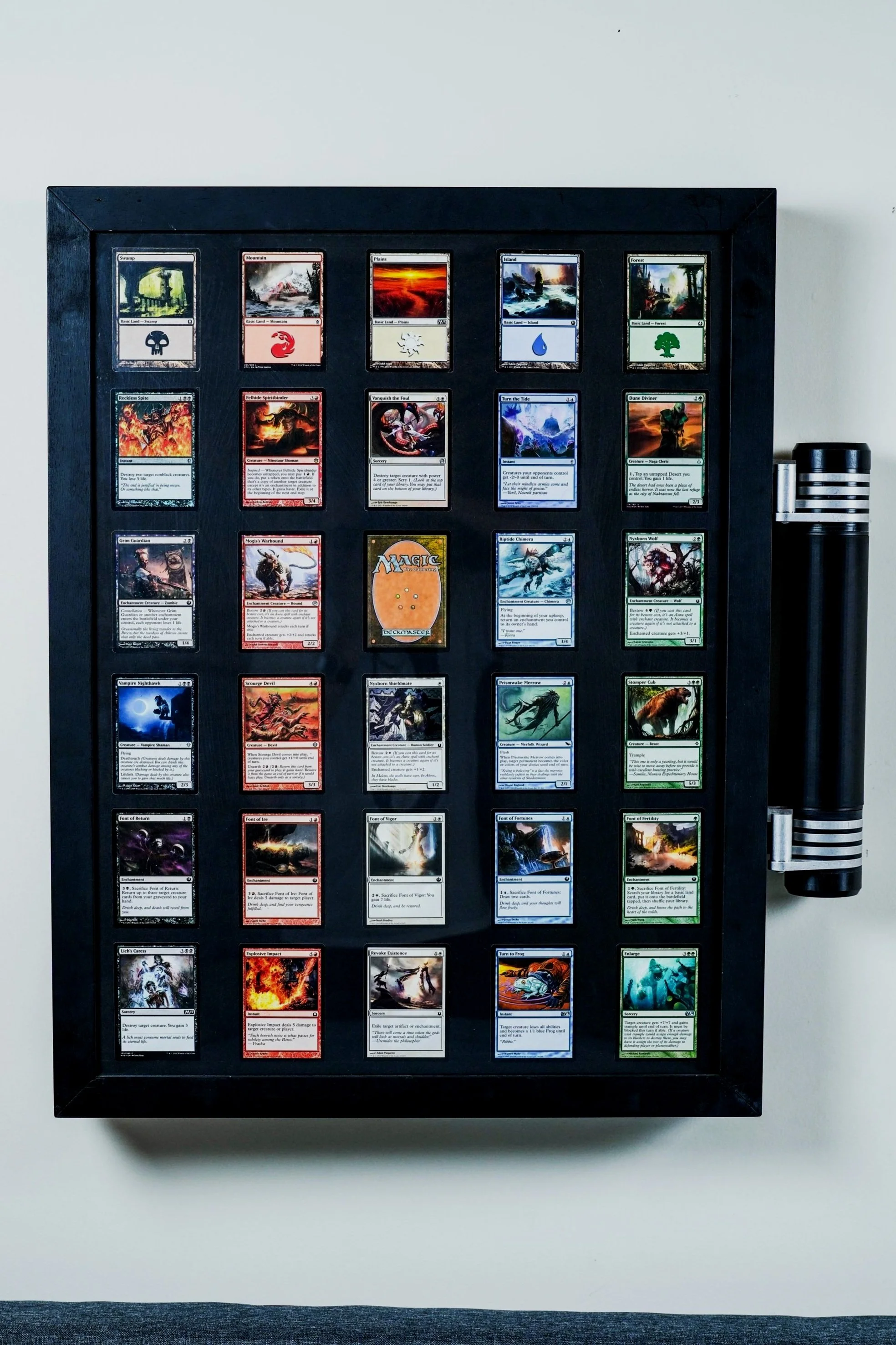 A black display case containing arranged Magic: The Gathering trading cards with various artwork and colors.