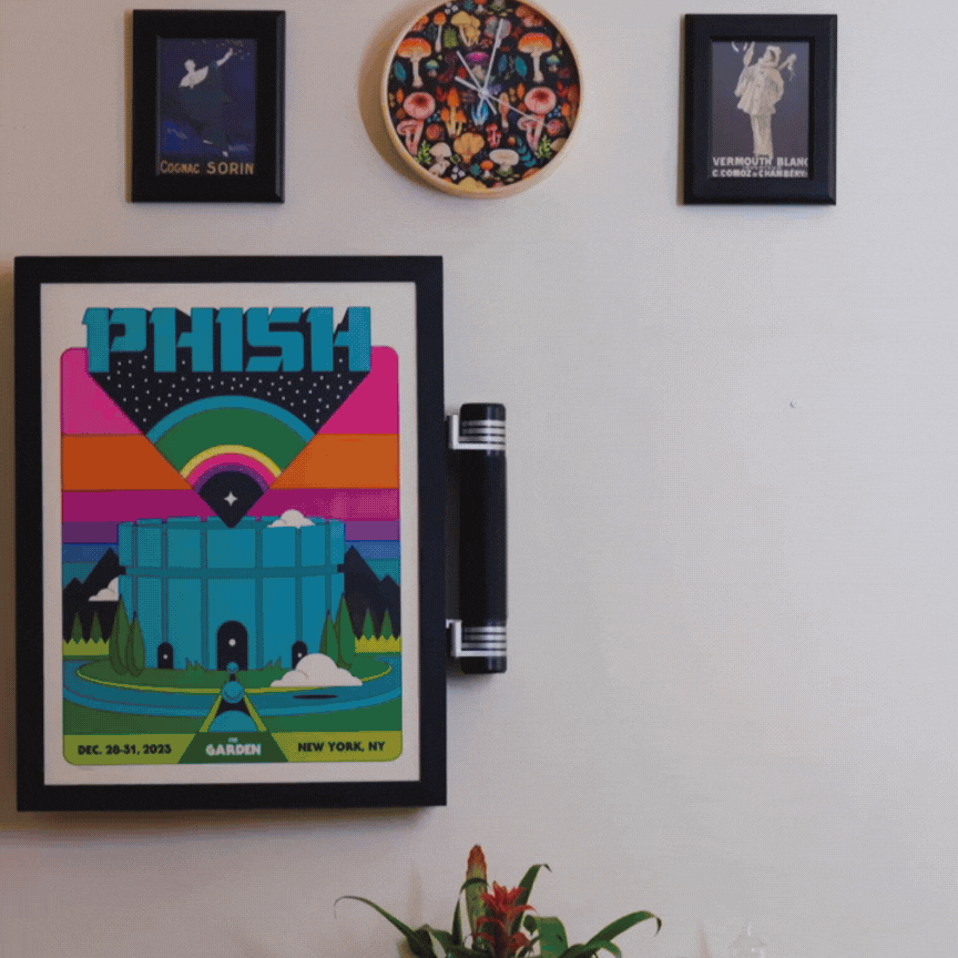 Decorative wall art and framed posters, including a colorful illustrated poster for a Phish concert in New York with a castle and rainbow, and a potted plant at the bottom.