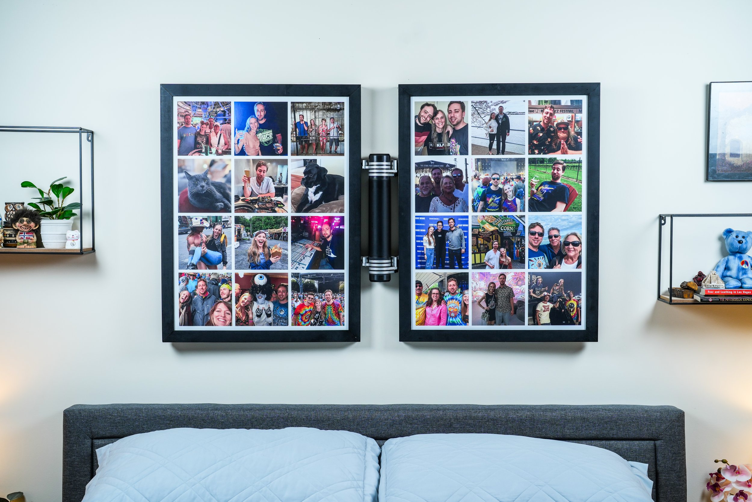 Decorative photo collage with multiple pictures of people at various events, including outdoor and indoor settings, some with pets, with a black frame, hanging on a white wall in a bedroom above a gray headboard and white bedding.