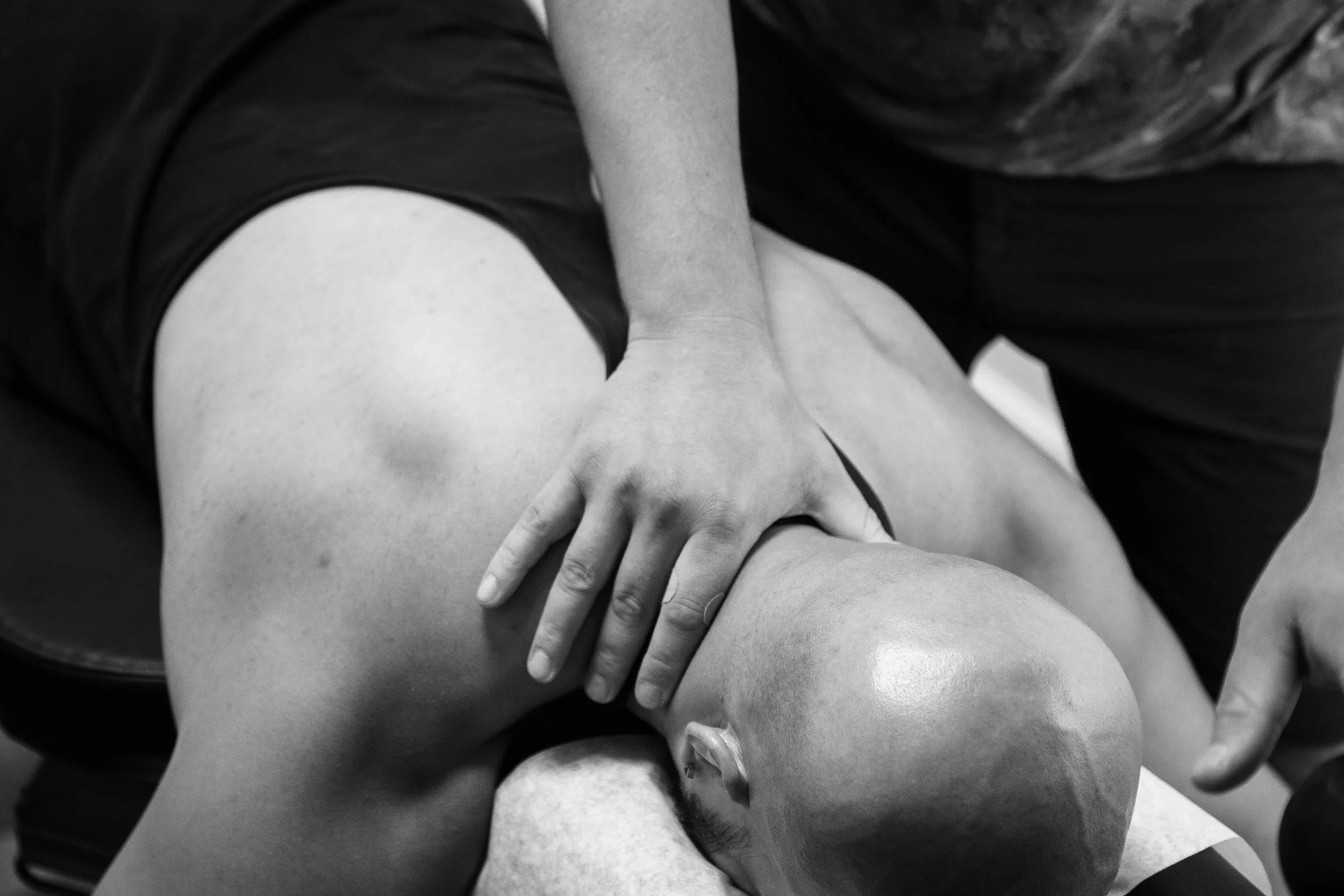 A person receiving a massage, lying face down on a massage table, with another person standing over them providing the massage.