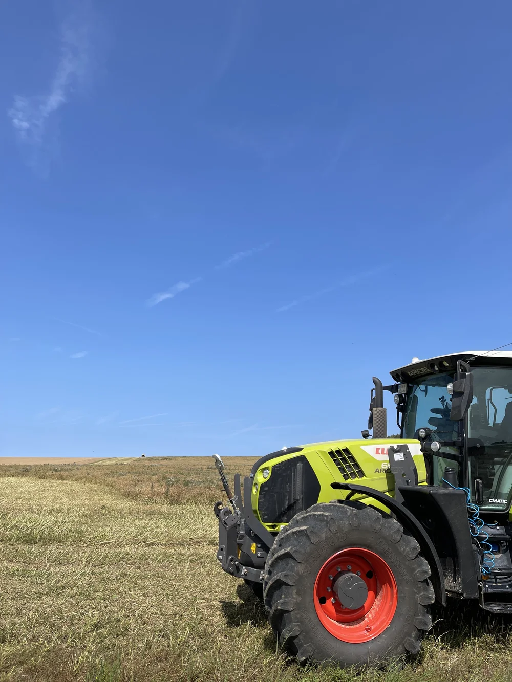 Traktor auf einem abgeernteten Feld unter blauem Himmel