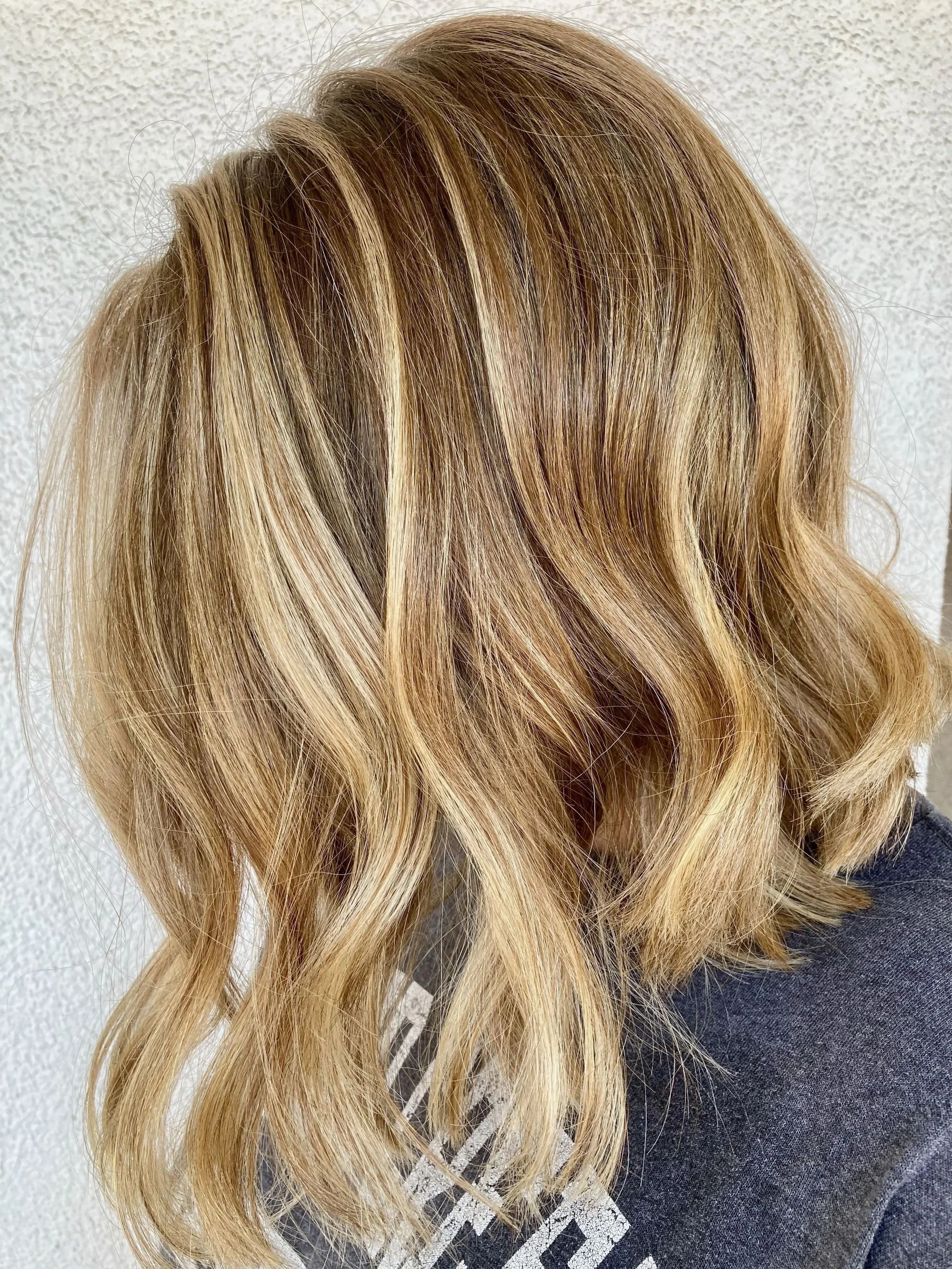 Side view of shoulder-length, wavy, blonde hair with highlights