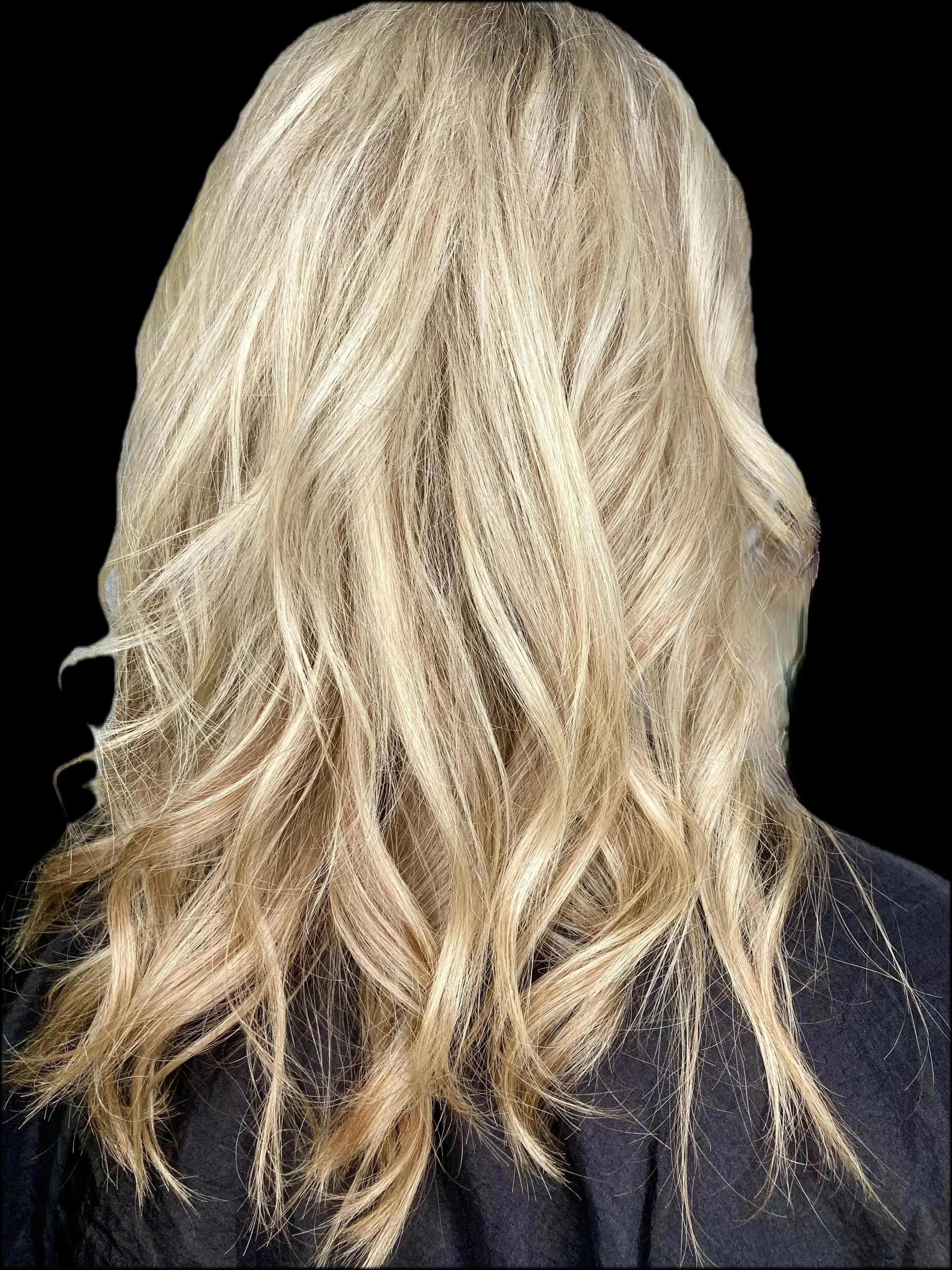 Blonde wavy hair viewed from the back with black background.