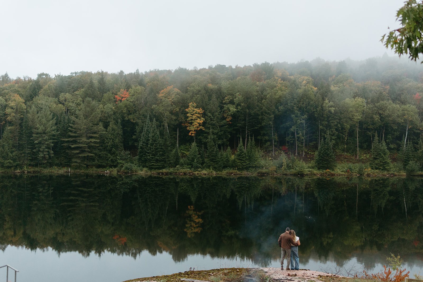 Engaged couple look at the lake on a moody foggy day in Low, Quebec