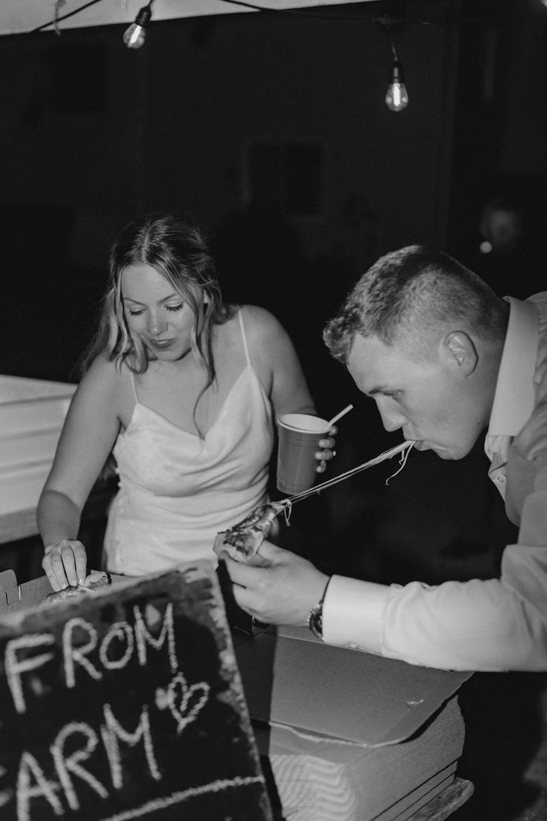bride and groom share pizza at their wedding reception