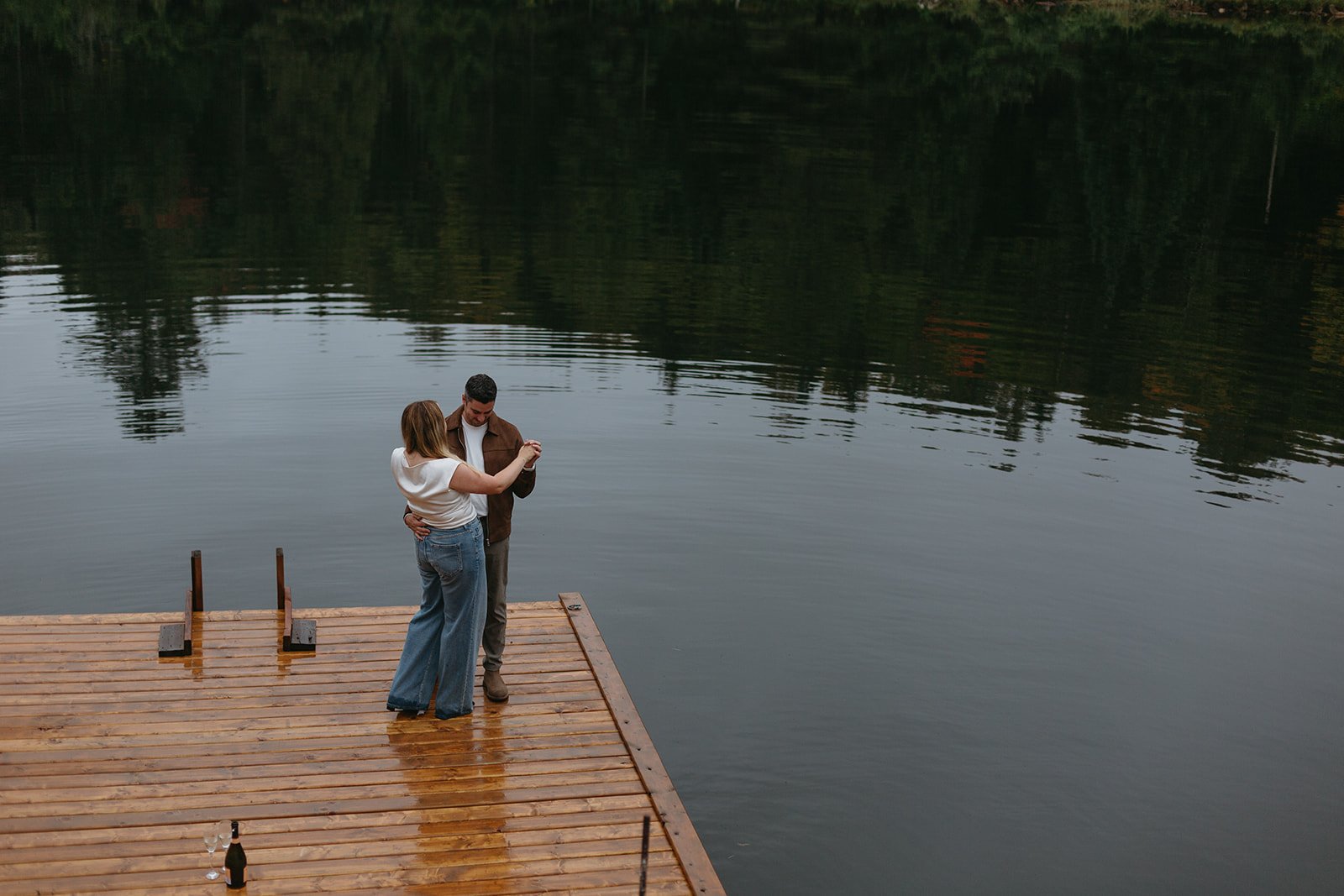 Newly engaged couple dance on the dock at their cottage in rural Quebec