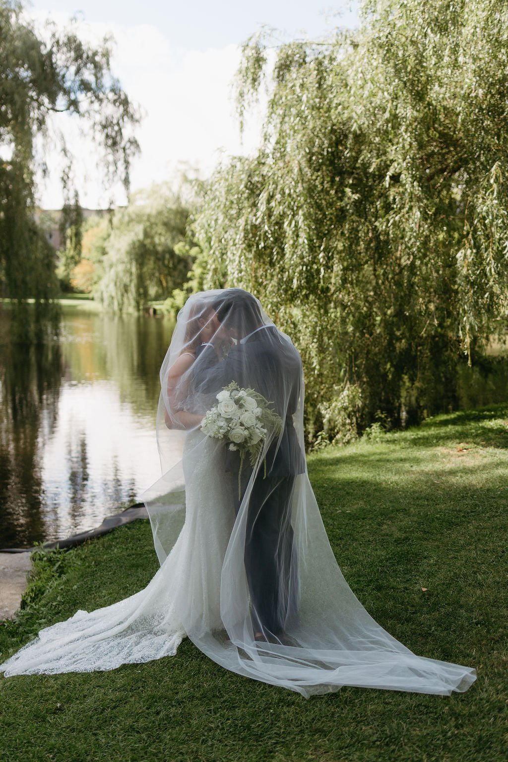 Bride and groom kiss under veil at Stewart Park elopement in Perth Ontario