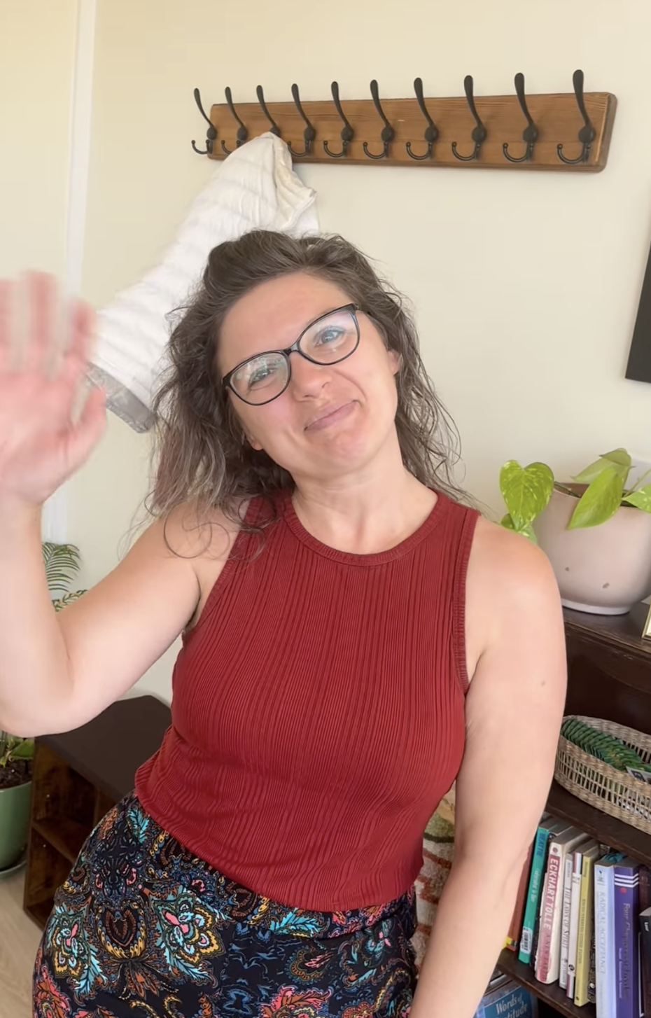 Portrait of a woman with short dark hair, wearing colorful patterned top, standing against a plain light-colored wall.