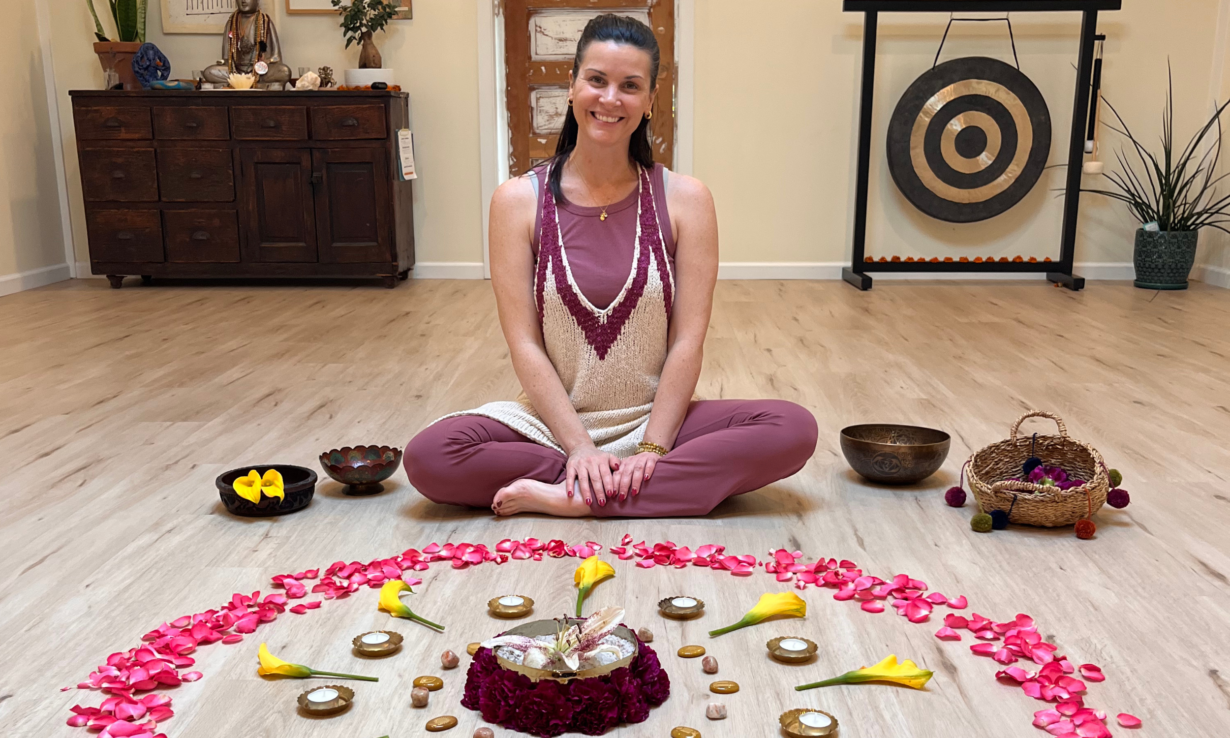 Woman sits in yoga studio in front of colorful flowers