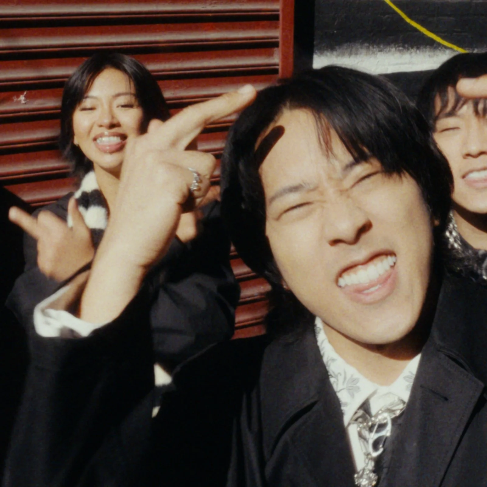 A group of young adults making playful faces and hand gestures at a social gathering or event.