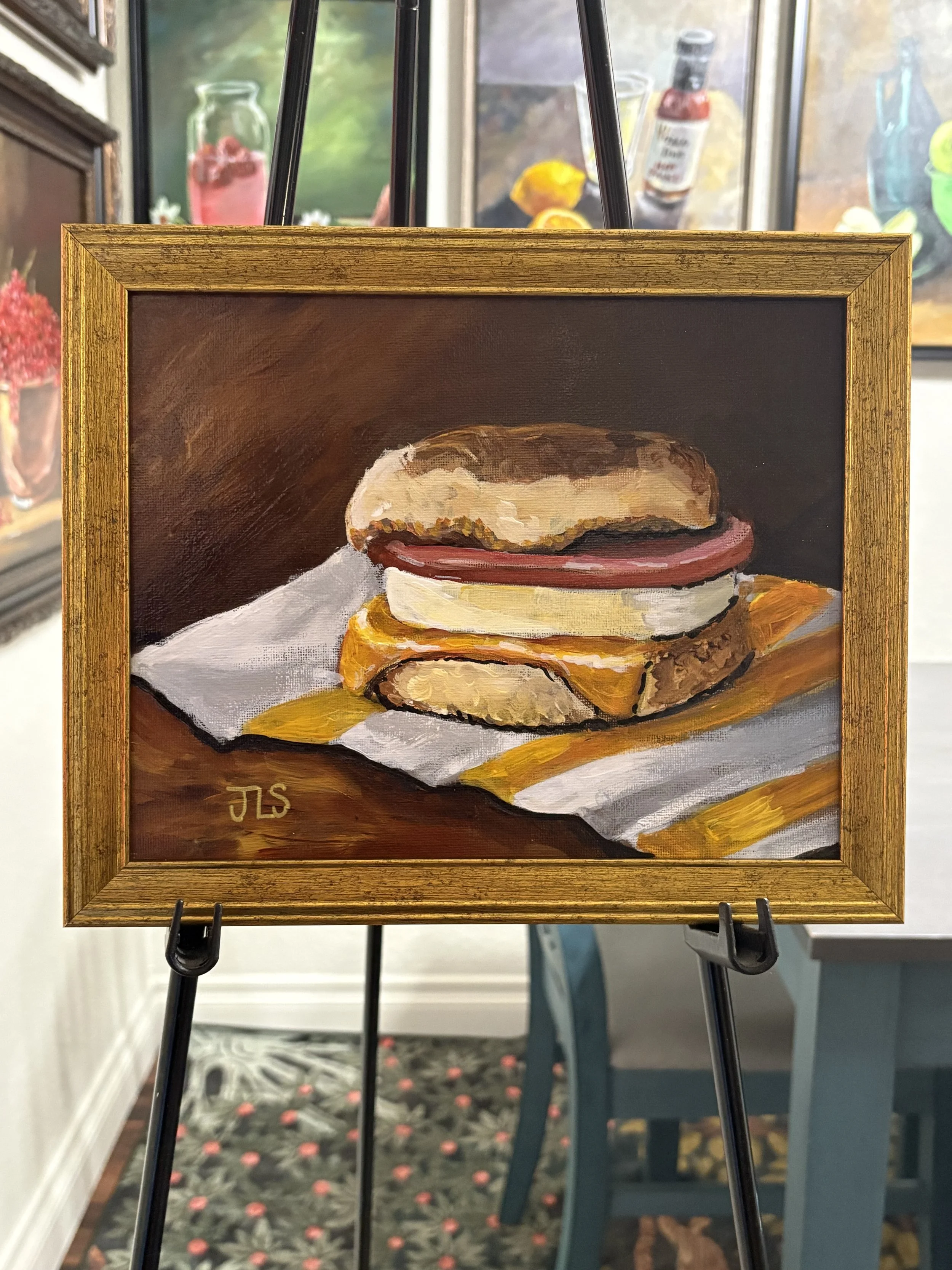 Painting of an Egg McMuffin, hand painted in acrylic on an 8 × 10 canvas panel and framed in a gold wood frame.