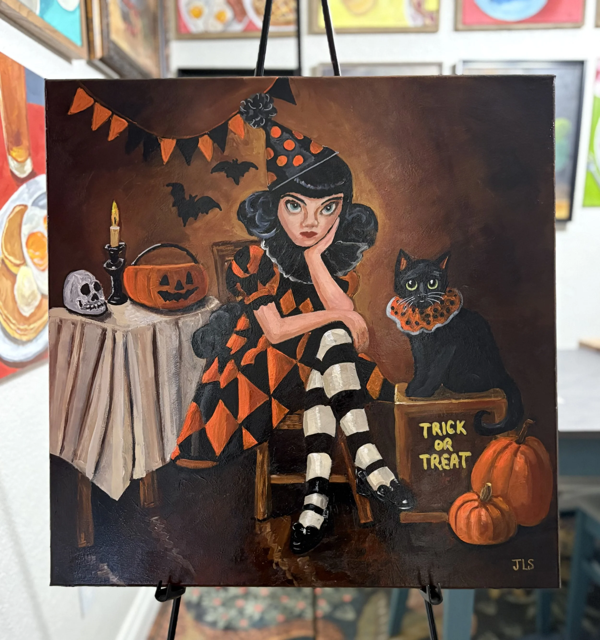 Original 24 x 24 inch acrylic painting of Delilah in a black and cream Halloween dress with her black cat Jasper, surrounded by pumpkins, candy, bats and candlelight.