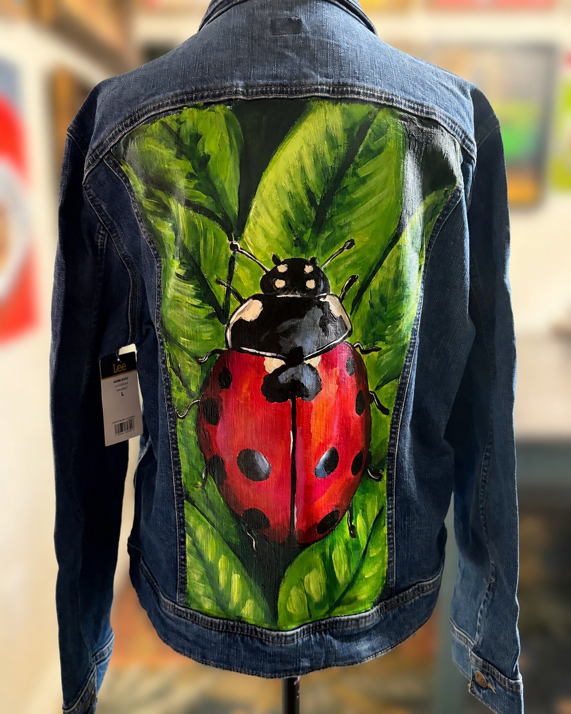 ee Rider denim jacket with a hand-painted red and black ladybug and green leaves on the back.