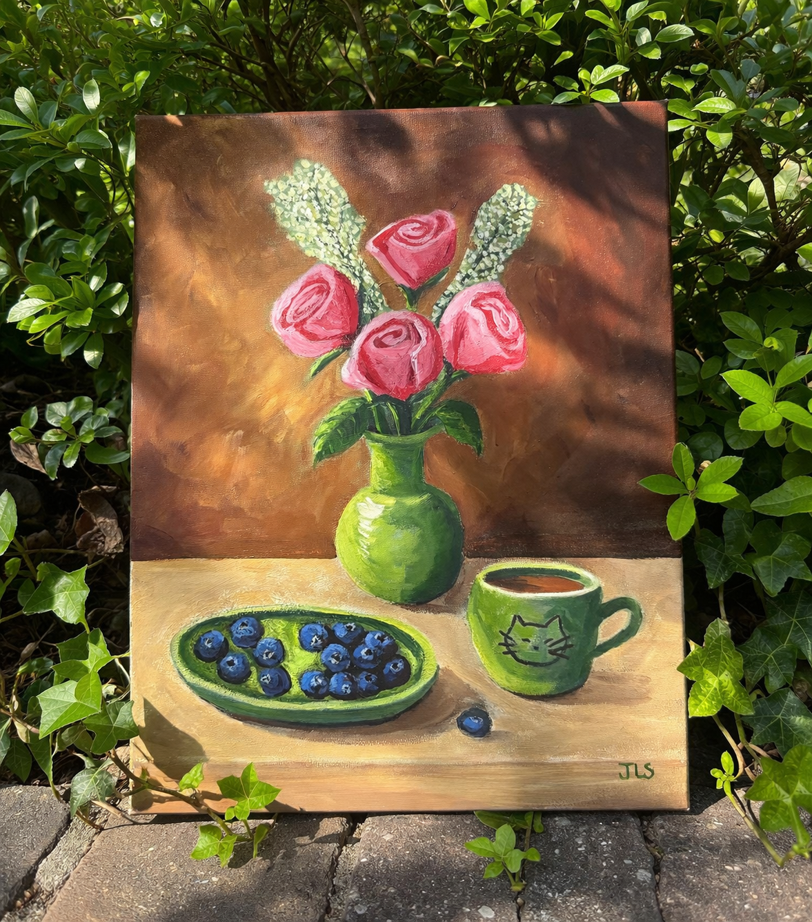 pink roses in a green vase on a table with a green cup and a bowl of blueberries