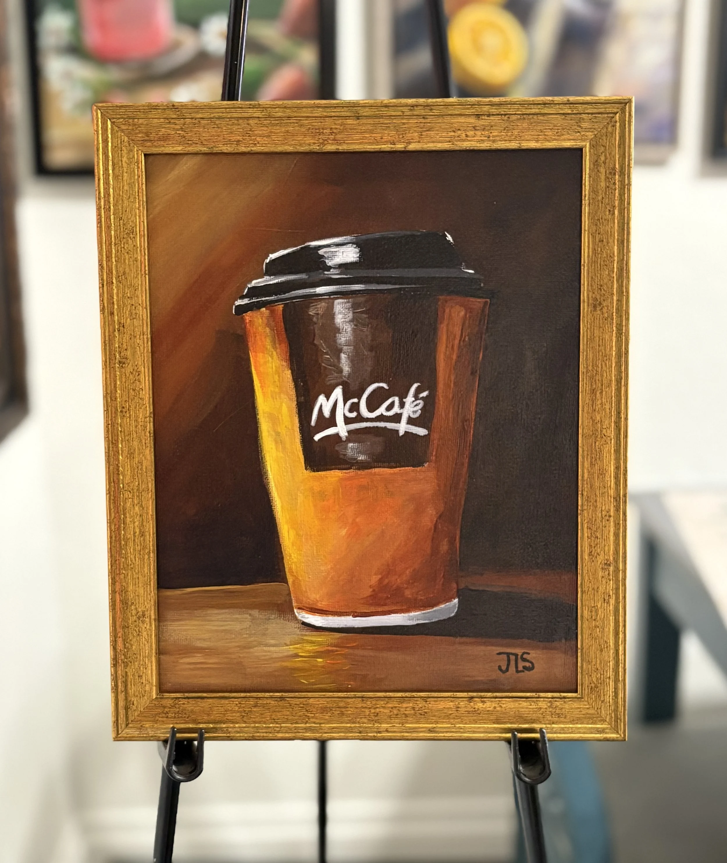 Painting of a McDonald’s McCafé coffee cup against a warm, moody brown background.
