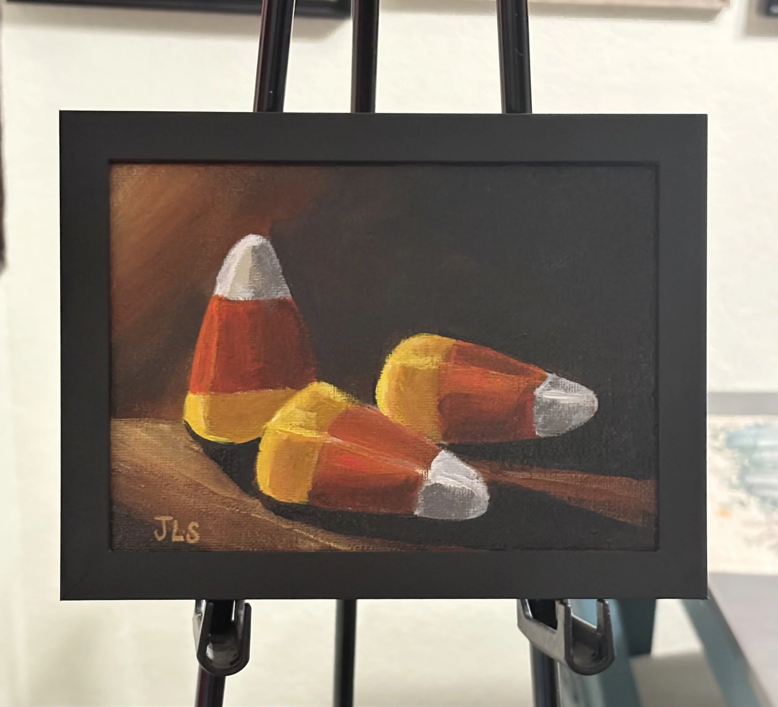 Candy Corn original hand painted acrylic still life by Jane L. Sayers featuring three pieces of candy corn against a dark moody background.