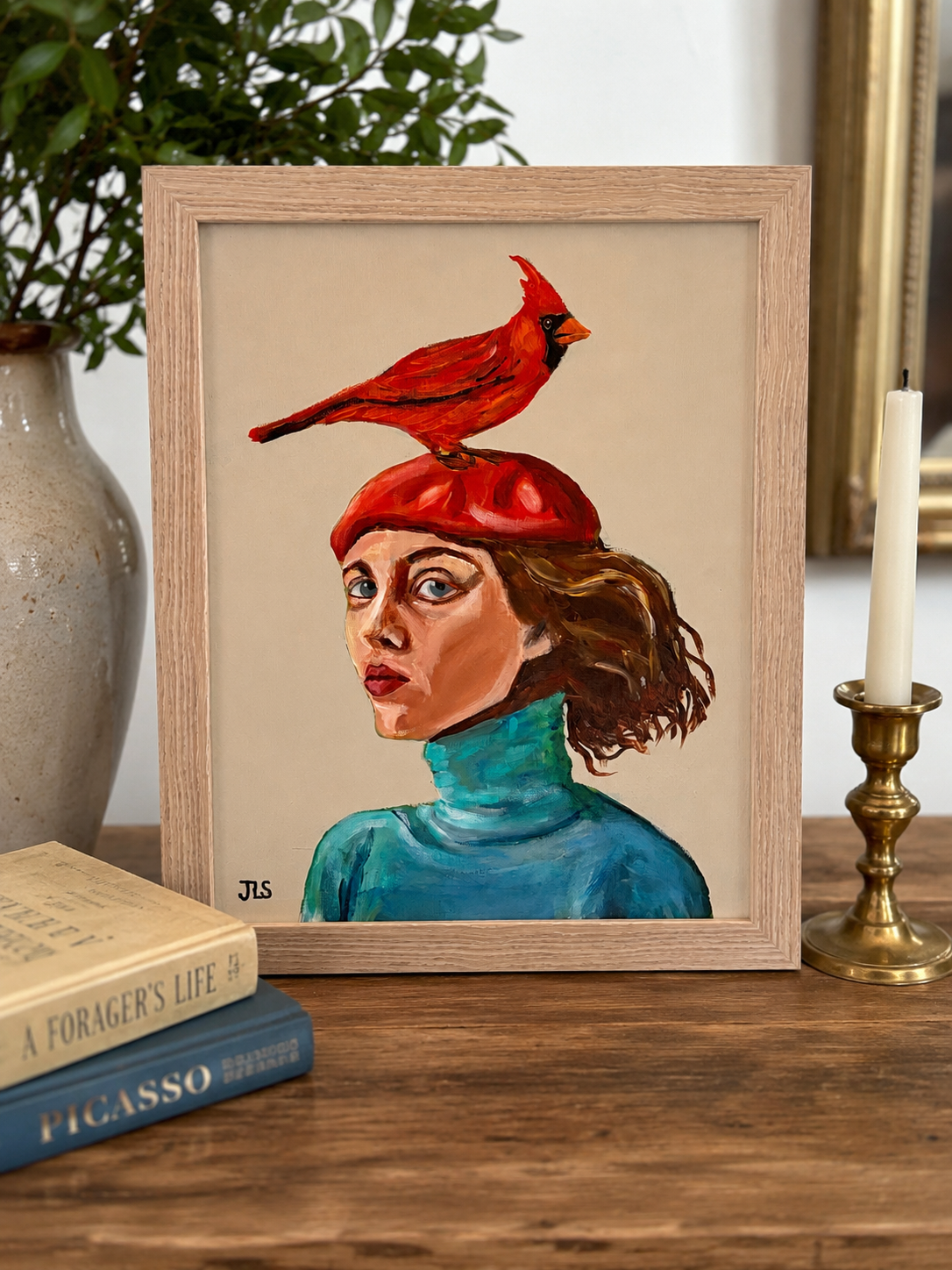 Woman in teal turtleneck and red beret with a red cardinal perched on top against a neutral background.