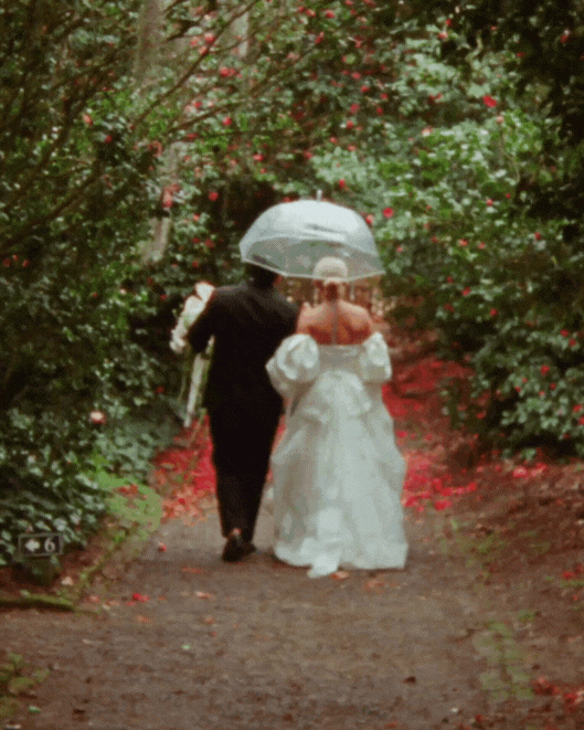 Black and white photo of two people in wedding attire lying on grass.