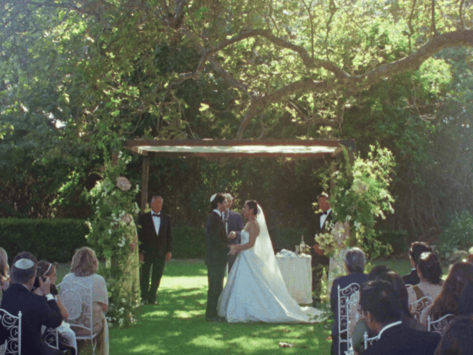 Bride holding yellow and peach bouquet walking with groom in dark suit.