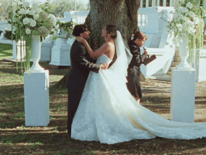 Bride holding yellow and peach bouquet walking with groom in dark suit.