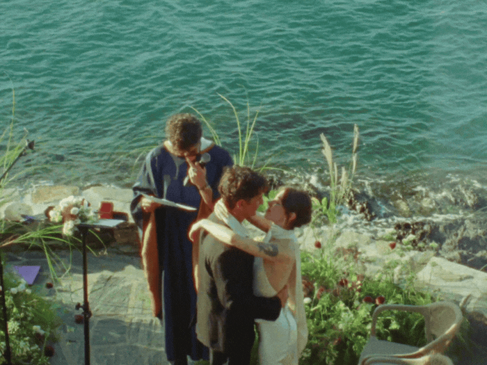 Bride holding yellow and peach bouquet walking with groom in dark suit.