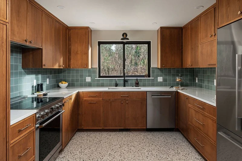 Sammamish WA kitchen remodel by a design-build remodeling contractor featuring custom mid-century wood cabinetry, green tile backsplash, terrazzo flooring, and a modern open layout