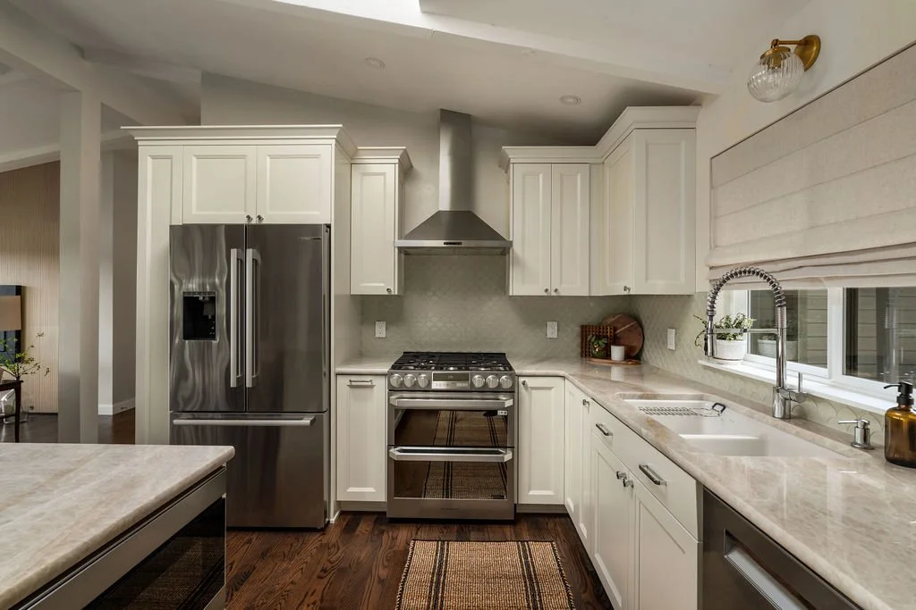 Remodeled kitchen in a Gig Harbor home featuring white cabinetry, stainless steel appliances, tile backsplash, and updated finishes by a remodeling contractor.
