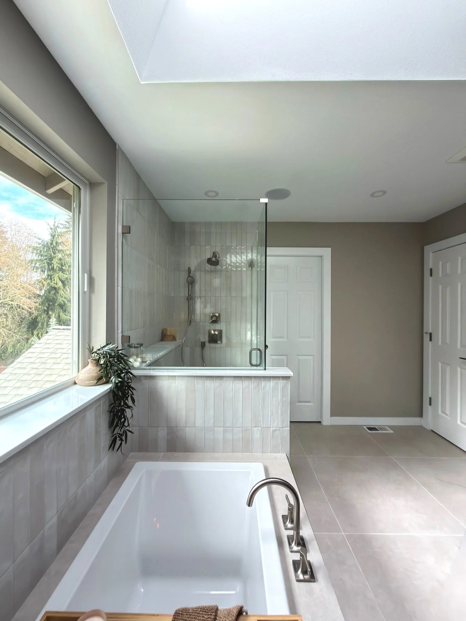 Freestanding soaking tub with tiled surround and walk-in shower in a Sammamish bathroom remodel with natural light