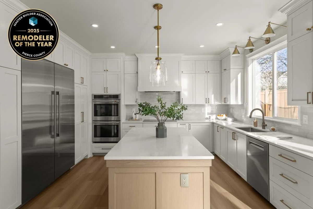White kitchen remodel by Massey Remodel + Design featuring shaker cabinets, brass lighting, and a large island with the 2025 Remodeler of the Year badge.