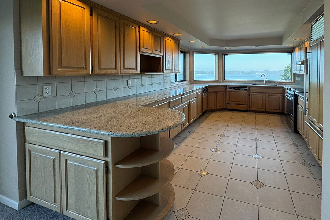 Before photo of a Browns Point Tacoma WA kitchen remodel showing dated wood cabinetry, tile floors, peninsula counter, and original layout prior to renovation by a professional contractor