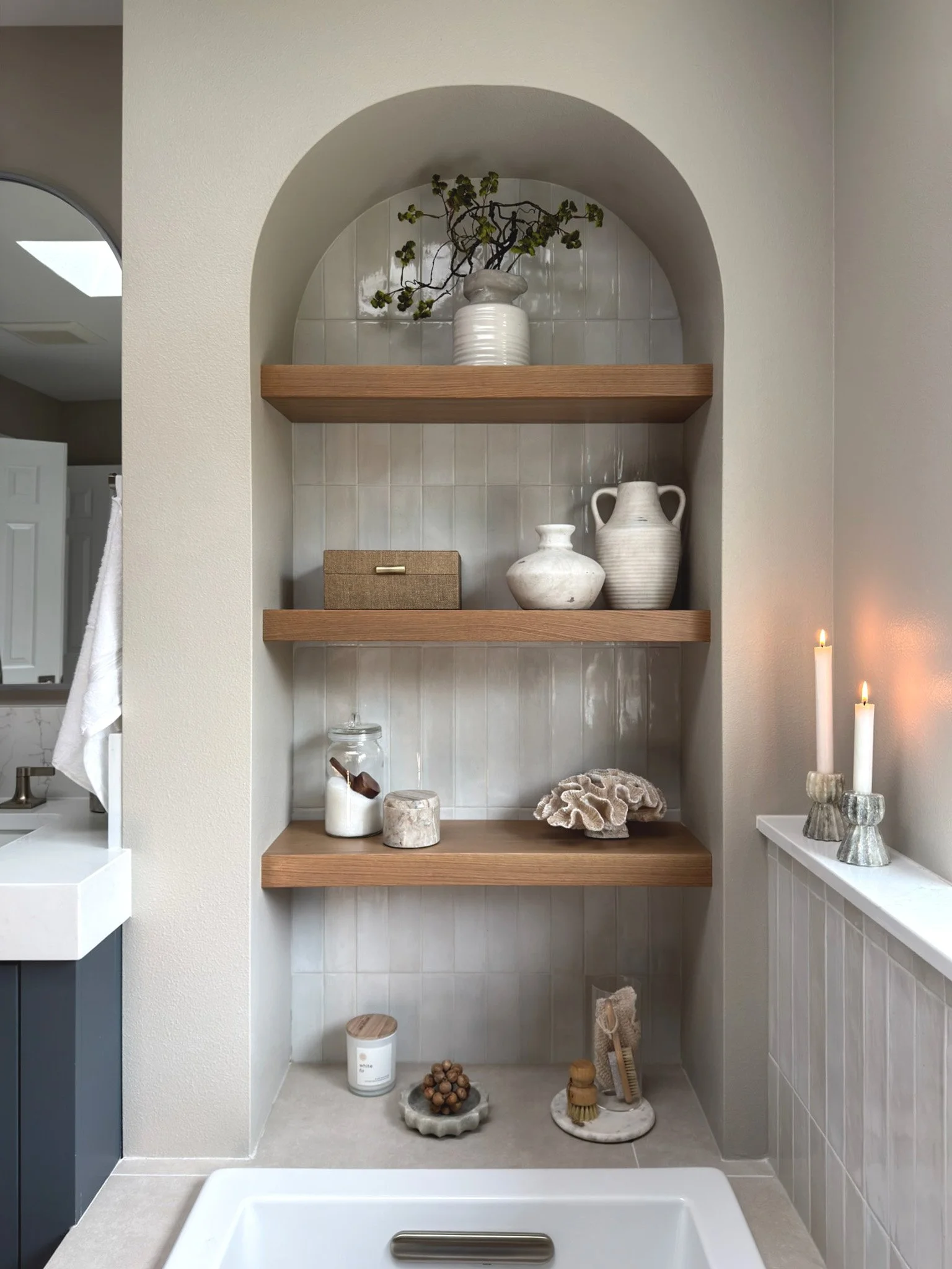 Arched built-in alcove shelving with warm wood shelves and tile backing in a modern bathroom remodel in Sammamish Washington