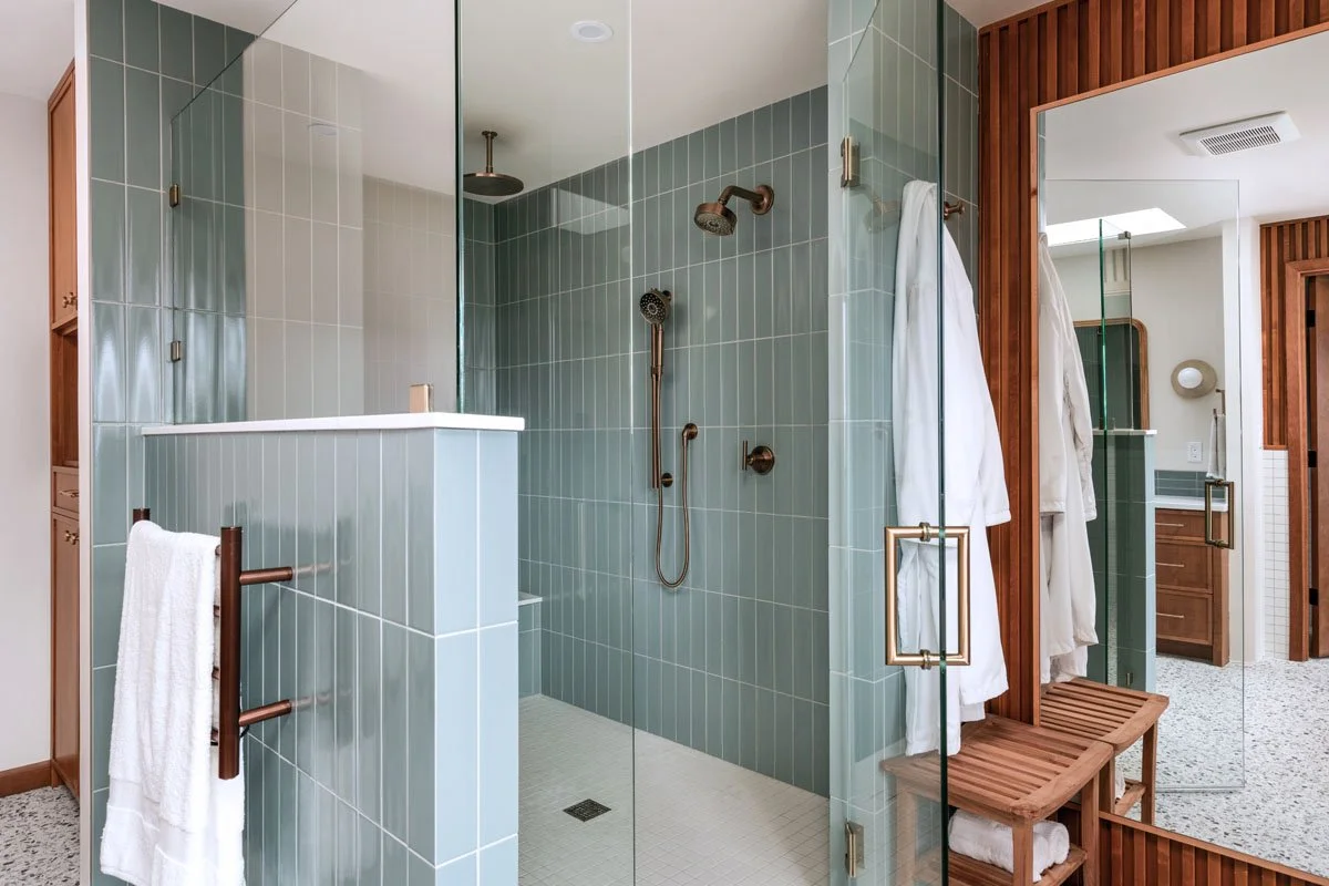 Mid-century bathroom remodel in Sammamish WA by a professional remodeling contractor featuring a custom glass shower, green tile walls, and modern brass shower hardware
