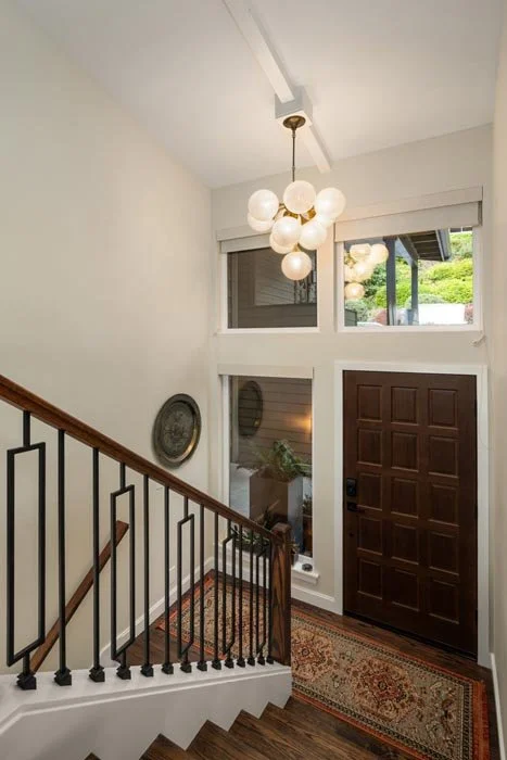Entryway foyer and staircase in a Gig Harbor home remodel, featuring a globe chandelier, updated stair railing, and modern finishes by a remodeling contractor.