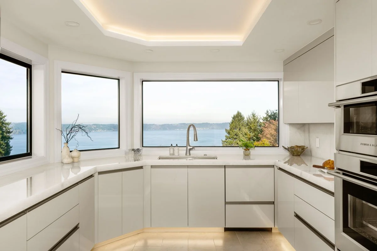 Tacoma WA kitchen renovation by an interior designer featuring European inspired cabinetry, Crystallo quartzite countertops, full height backsplash, and panoramic waterfront windows
