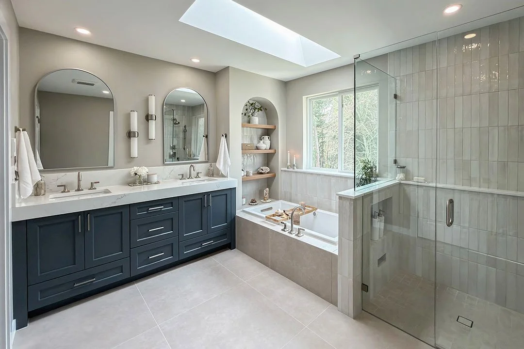 After photo of an award-winning Puyallup primary bathroom remodel featuring a custom navy vanity, quartz countertops, walk-in glass shower, soaking tub, designer tile, and luxury spa-inspired bathroom design.