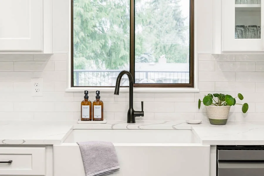 Award-winning kitchen remodel by Massey Remodel + Design with white cabinetry, apron-front sink, quartz countertops, and modern fixtures in Pierce County, Washington