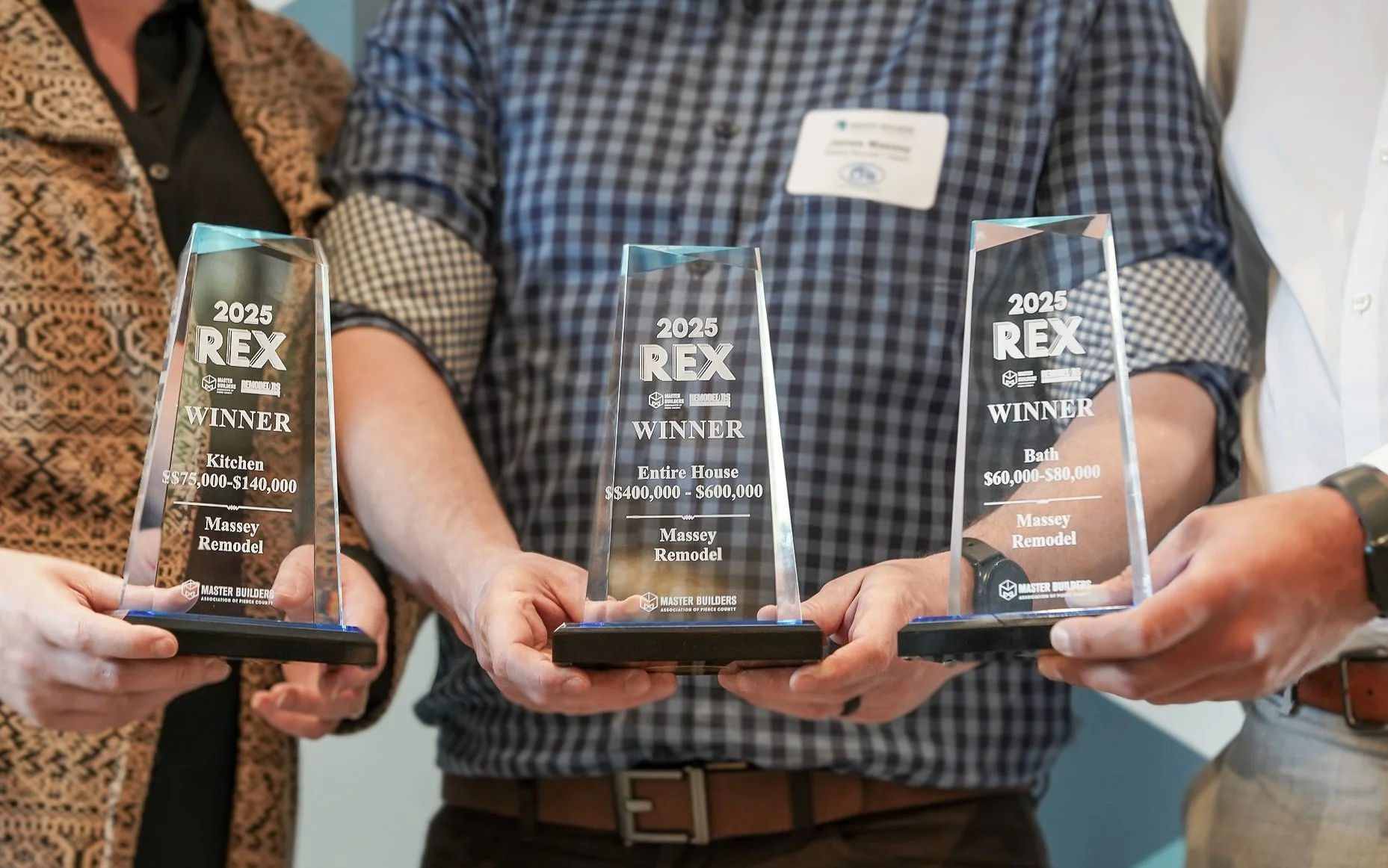 Massey Remodel + Design team holding 2025 REX Awards for remodeling excellence from the Master Builders Association of Pierce County in Tacoma, Washington