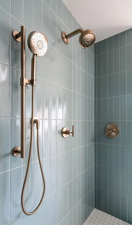 Sammamish WA bathroom remodel by a design-build remodeling contractor featuring a mid-century modern tiled shower with brushed brass fixtures and green ceramic tile