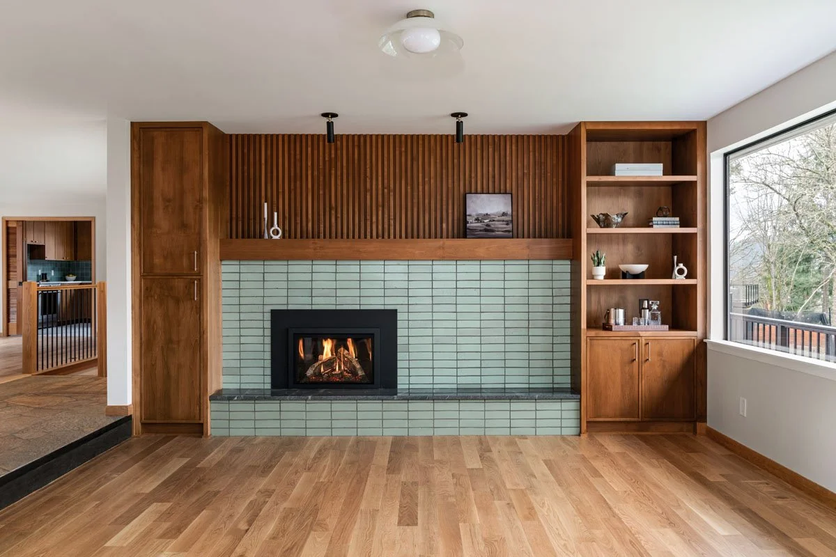 Mid-century living room remodel in Sammamish WA by a professional remodeling contractor featuring a tiled fireplace, custom slatted wood accent wall, and hardwood flooring
